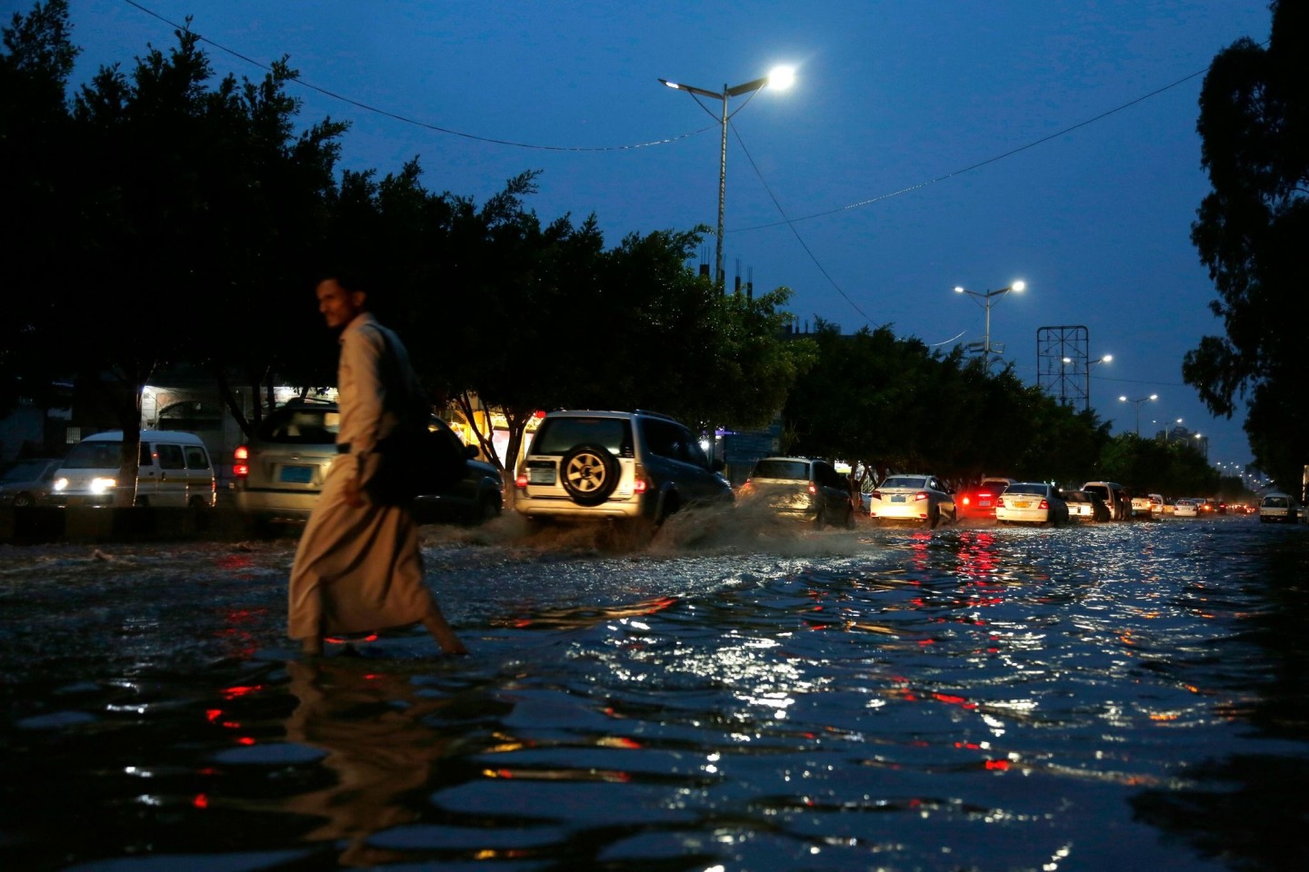 Ein Mann überquert in Sanaa eine stark befahrene Straße, die nach heftigen Regenfällen überflutet ist.