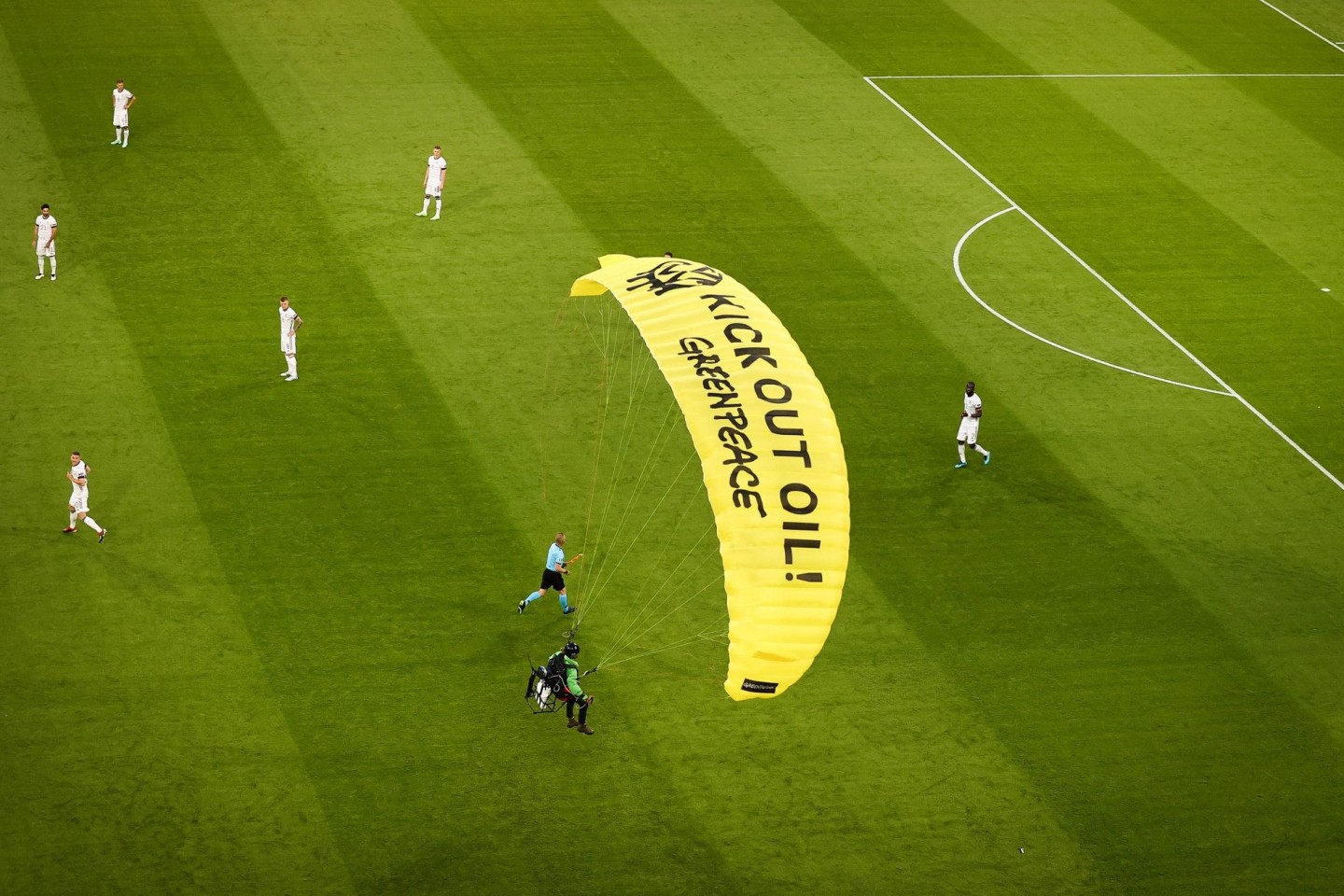 Ein Greenpeace-Aktivist landet mit einem Motorschirm-Flieger bei einer Protestaktion auf dem Spielfeld.