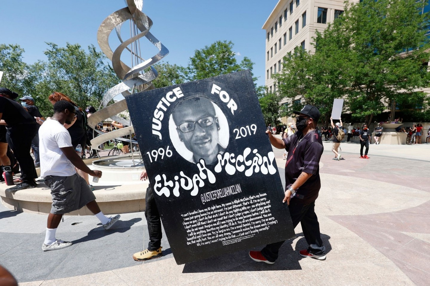Demonstranten tragen während einer Kundgebung vor dem Polizeirevier wegen des Todes von Elijah McClain ein Plakat mit dessen Bild.
