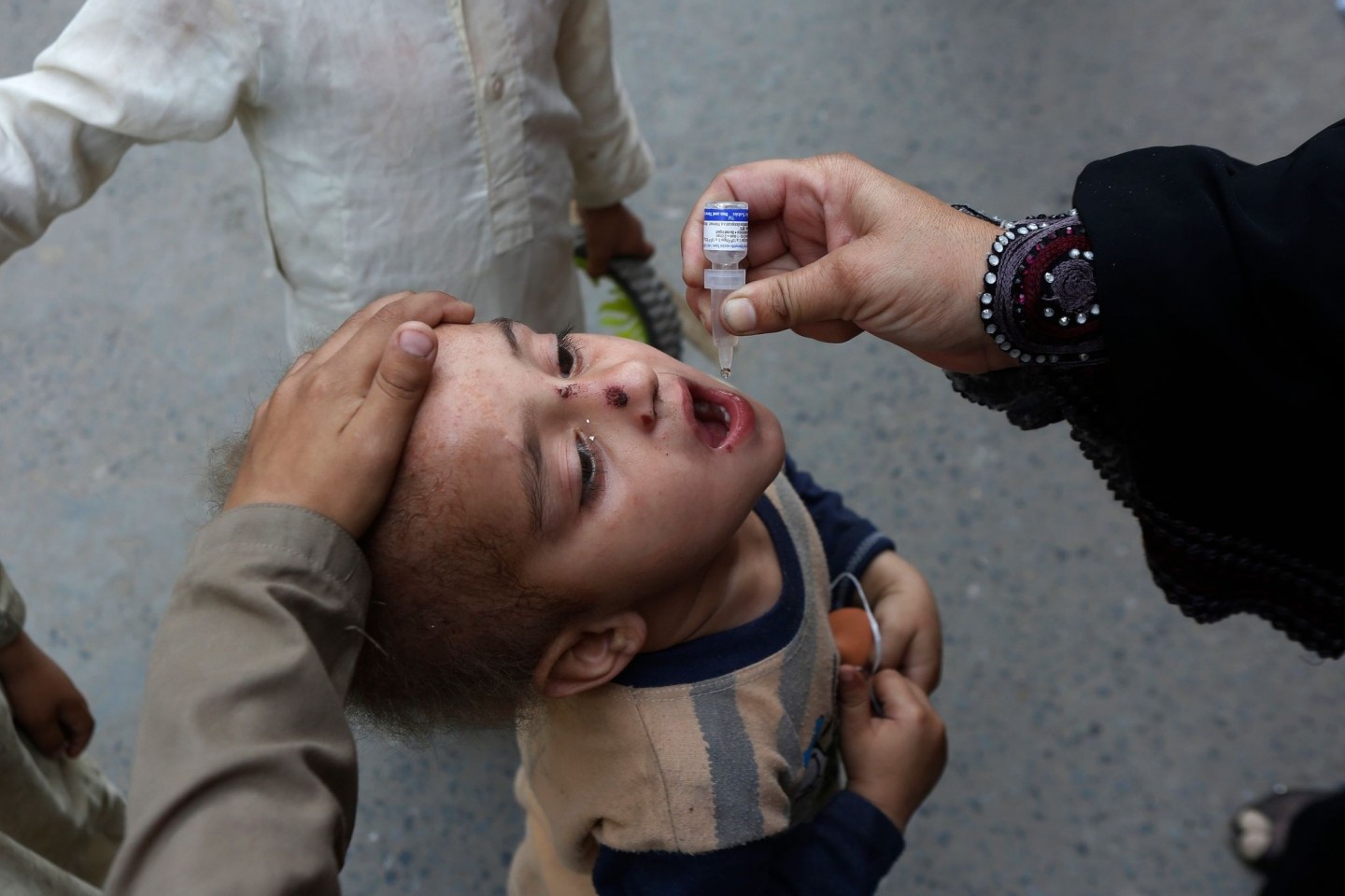 Ein Mitarbeiter des Gesundheitswesens gibt einem Kind eine Schluckimpfung gegen Polio (Kinderlähmung).