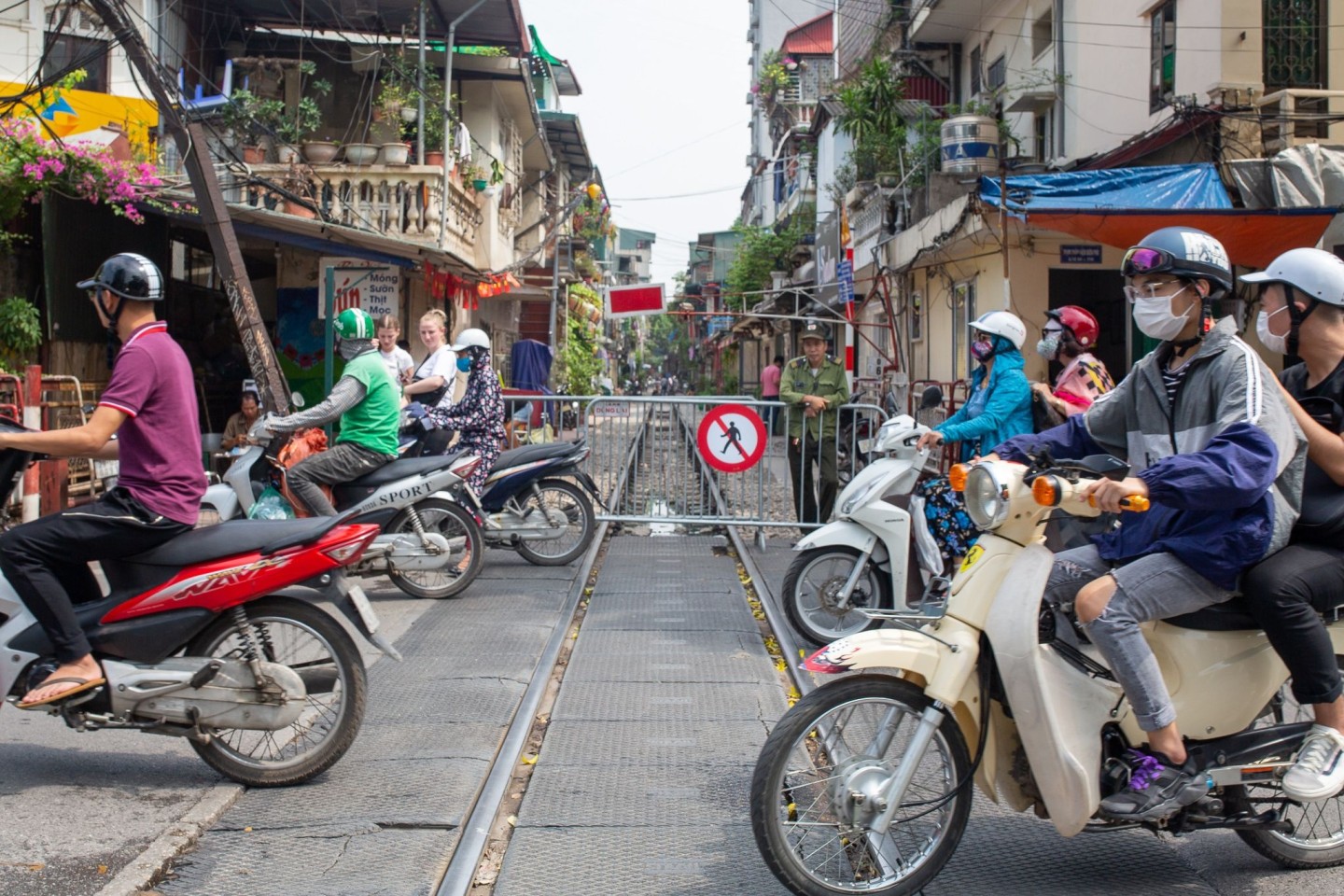 Motorradfahrer überqueren die Train Street in Hanoi, die für Fußgänger gesperrt ist.