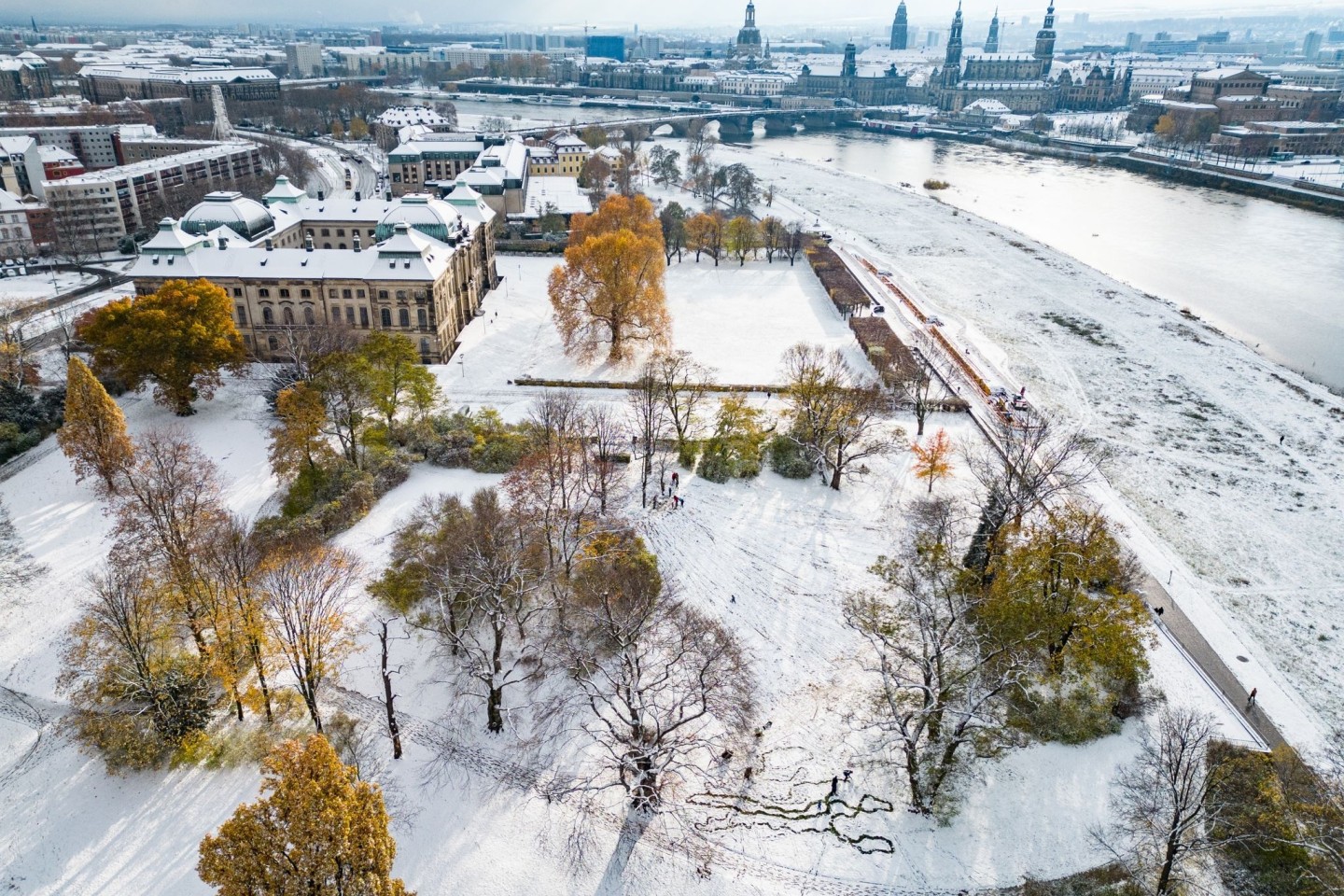 Die Wiesen am Elbufer vor der historischen Altstadt von Dresden sind mit Schnee bedeckt.